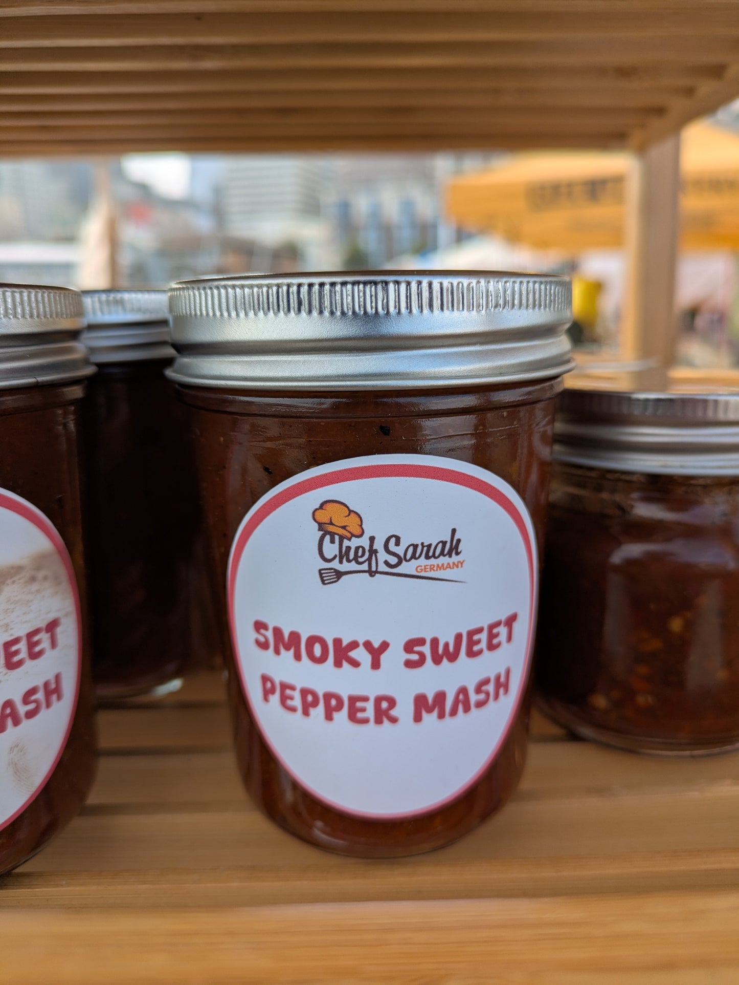Jar of 'Smoky Sweet Pepper Mash' with a label on a wooden shelf.
