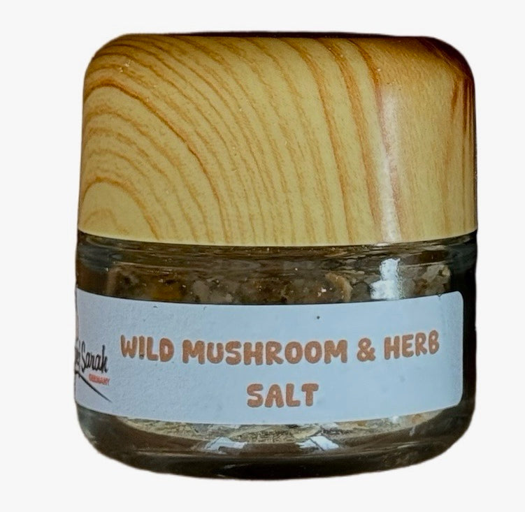 Jar of wild mushroom and herb salt with wooden lid on a white background