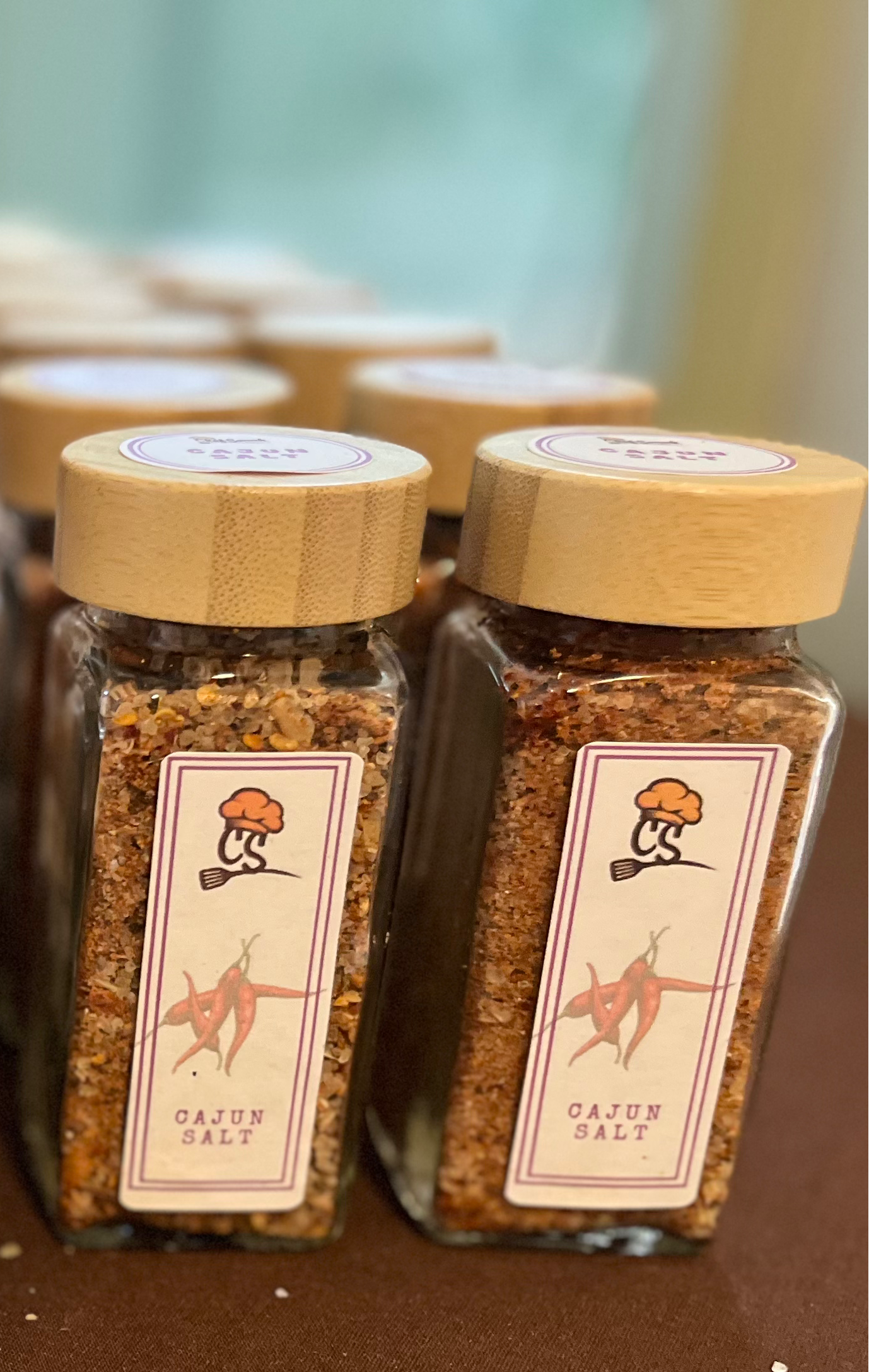 Collection of spice jars with wooden lids on a brown surface