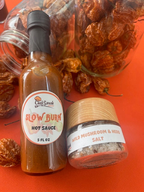 Hot sauce bottle and jar with dried peppers on an orange background