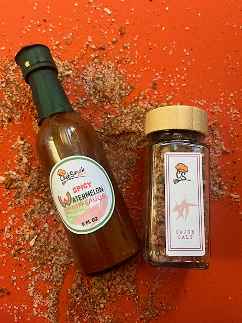 Hot sauce and a jar of salt with labels on an orange surface