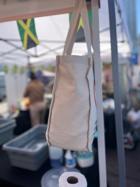 Beige tote bag hanging on a stand with a blurred background
